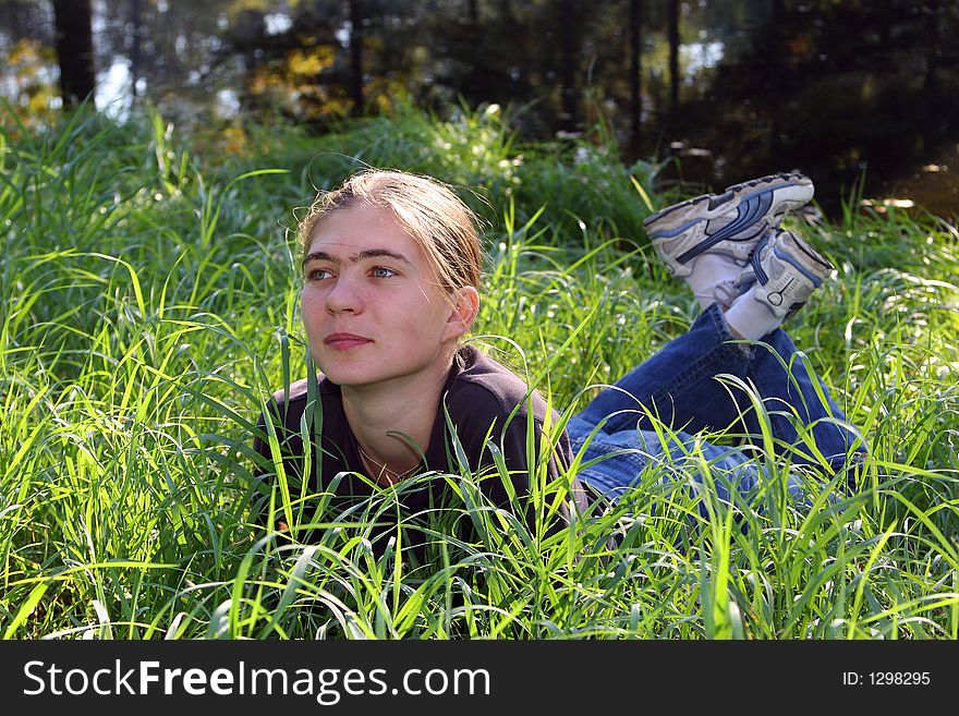 The joyful girl has a rest in a grass. The joyful girl has a rest in a grass