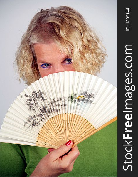 A self-confident, middle-aged woman holding an original japanese folding fan with filigree pattern. A self-confident, middle-aged woman holding an original japanese folding fan with filigree pattern.