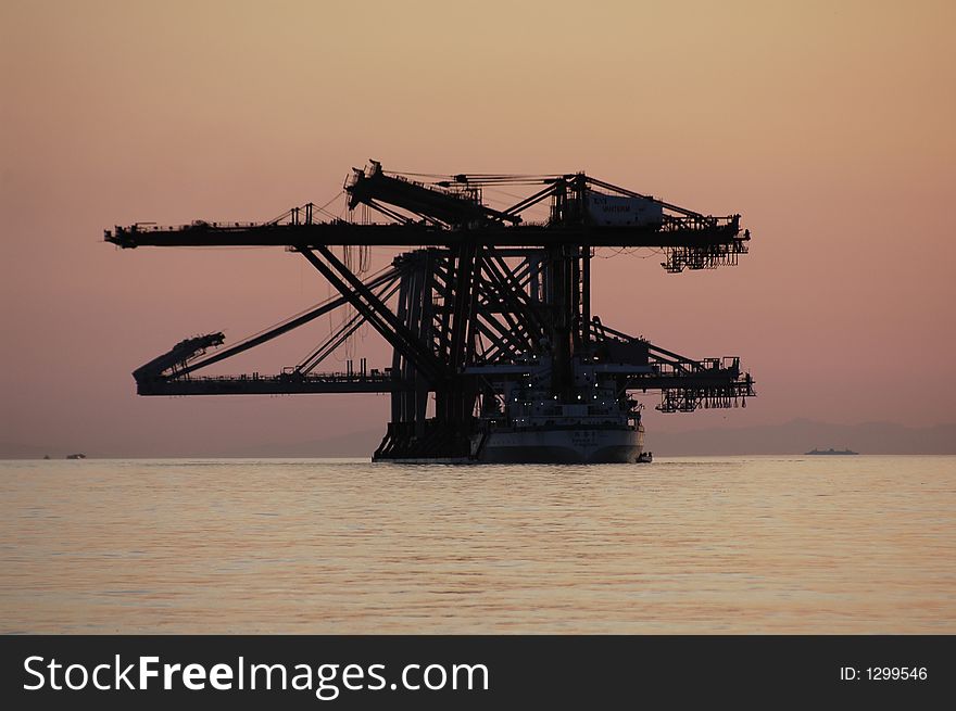 Large ship transporting dock loading machinery during a sunset. Large ship transporting dock loading machinery during a sunset.