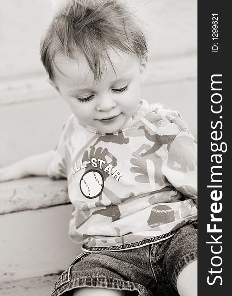 Black and white infant boy sitting on stairs with wind  blowing