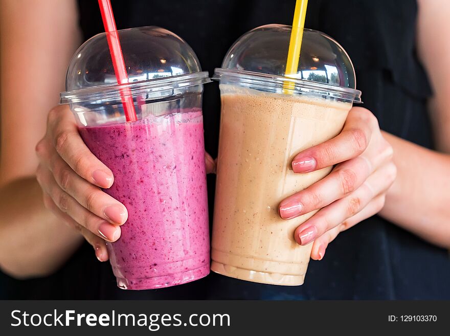 Close up woman`s hands holding two glasses with pink and orange berry smoothie. Close up woman`s hands holding two glasses with pink and orange berry smoothie