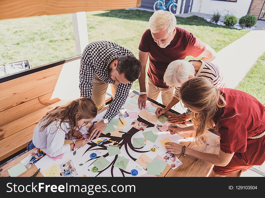 Pleasant interaction. Concentrated little girl bowing head while doing her family tree. Pleasant interaction. Concentrated little girl bowing head while doing her family tree