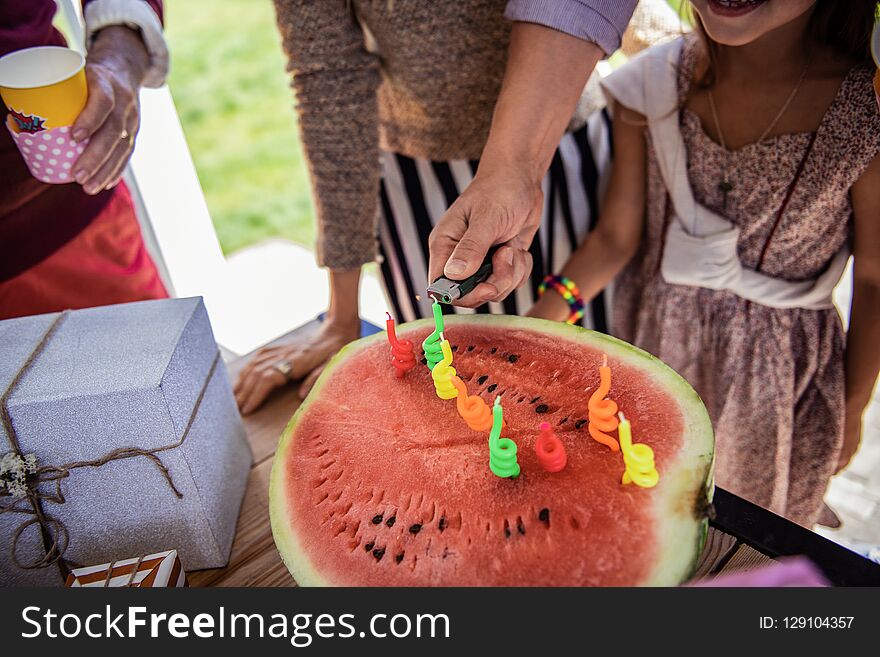 Festive atmosphere. Big watermelon standing on the table, little girl making wish. Festive atmosphere. Big watermelon standing on the table, little girl making wish