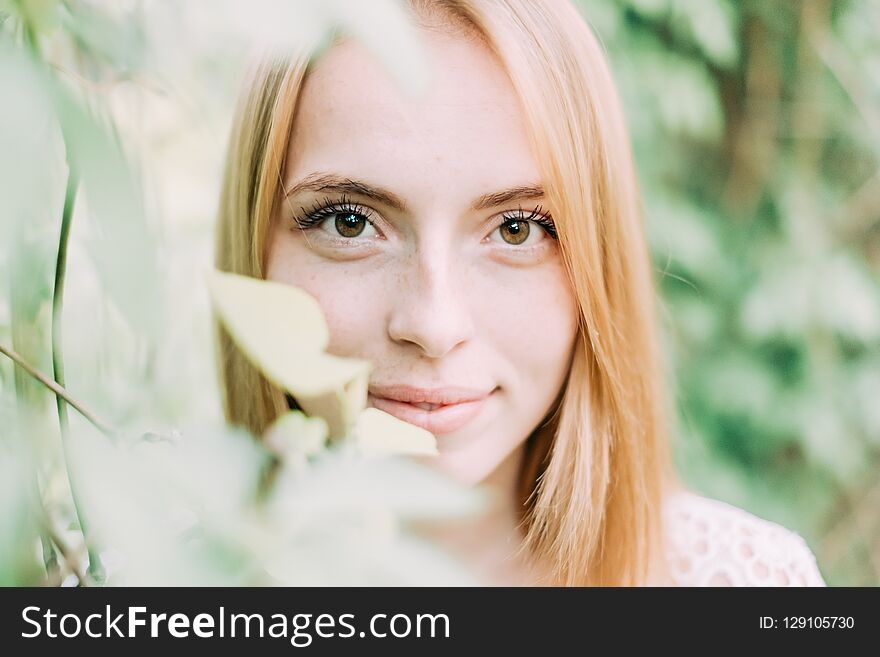 Beautiful attractive young woman posing in spring park wearing white knitted top and blue jeans, modern creative toning