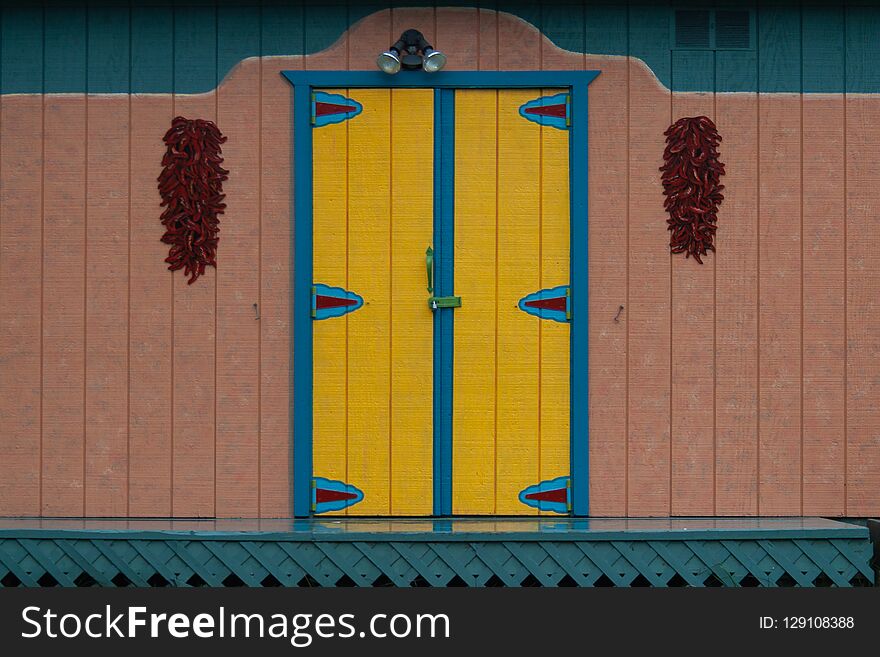 Colorful decorative Mexico door with some red peppers hanging on sides. Colorful decorative Mexico door with some red peppers hanging on sides.