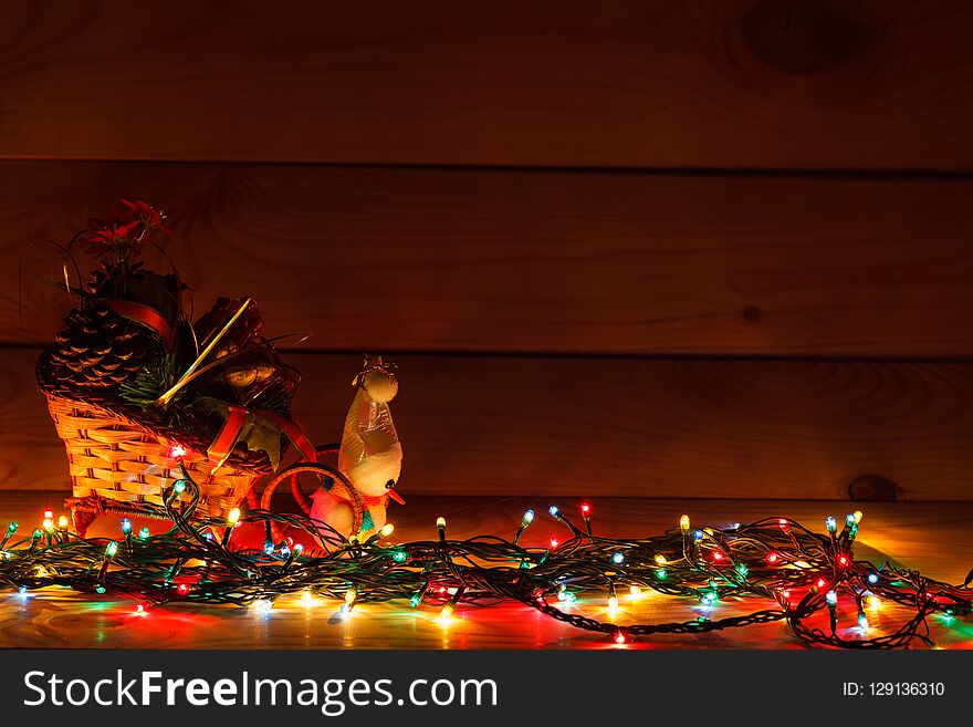 Christmas garland with a snowman in a sleigh with gifts. On wooden background.