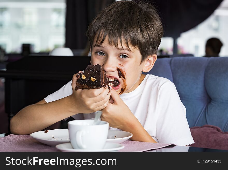 The boy is eating a large piece of cake in his hands