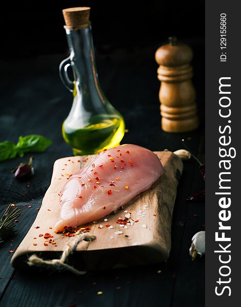 Raw chicken fillet with spices and on a dark background