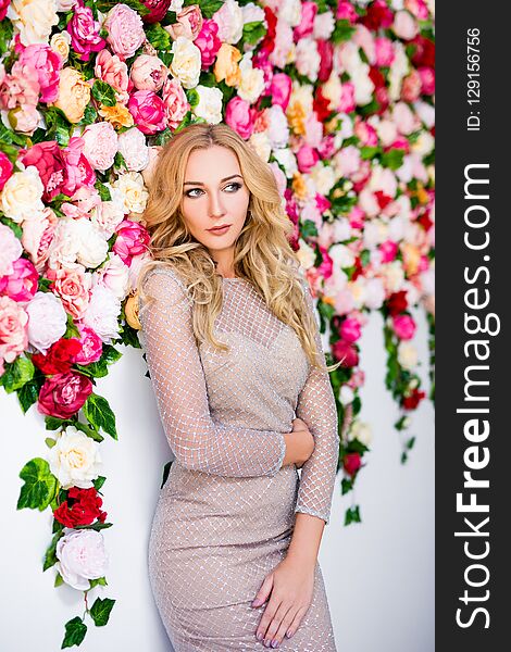 Portrait of beautiful blond girl in dress posing over colorful flowers background. Portrait of beautiful blond girl in dress posing over colorful flowers background