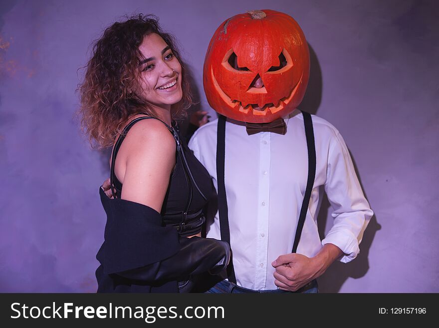 Unusual couple at Halloween party, Woman with pumpkin on head