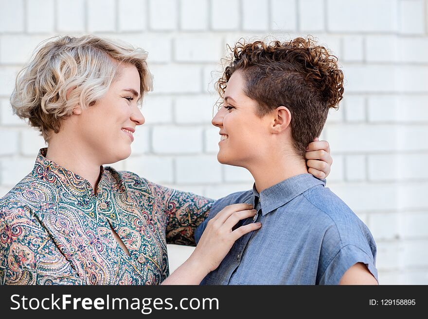 Affectionate young lesbian couple looking lovingly into each other`s eyes while standing together on a city street outside. Affectionate young lesbian couple looking lovingly into each other`s eyes while standing together on a city street outside