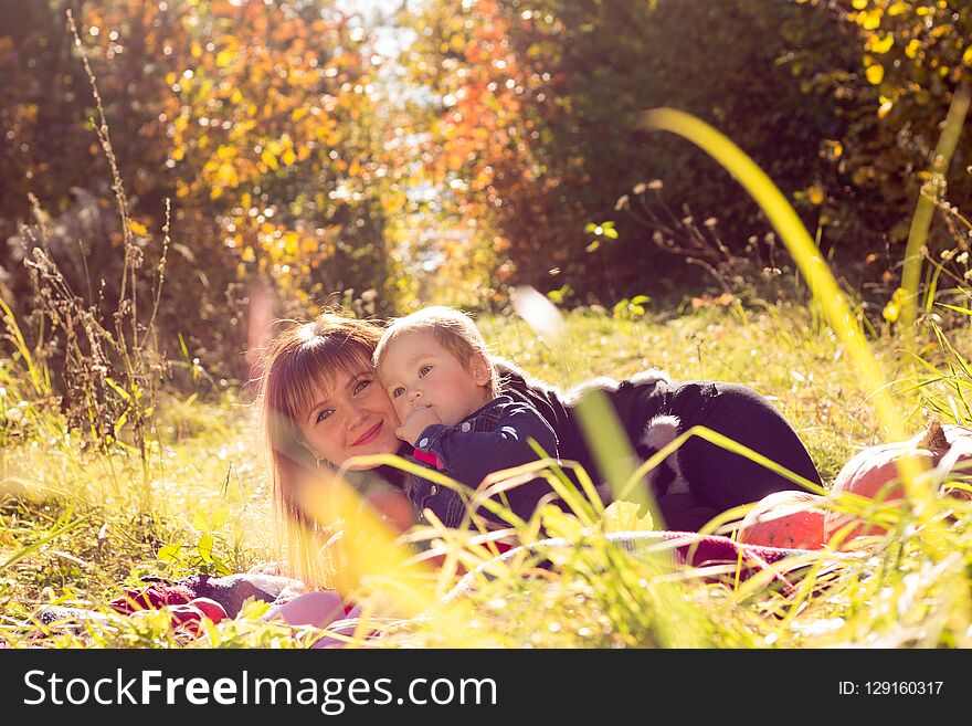 Mom and daughter lie in the grass against the background of autumn trees