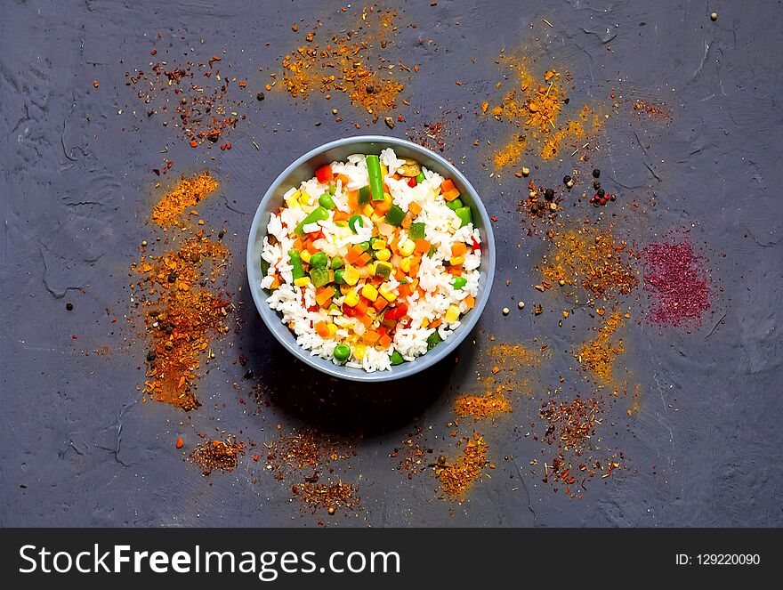 Rice with vegetables and spices on dark blue concrete background. Vegetarian food, products for proper nutrition, close up, copy space,flat lay.