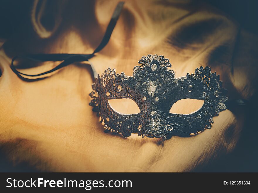 Luxury venetian ball mask on golden silk fabric. Masquerade vintage party or holiday event celebration concept. Luxury venetian ball mask on golden silk fabric. Masquerade vintage party or holiday event celebration concept.