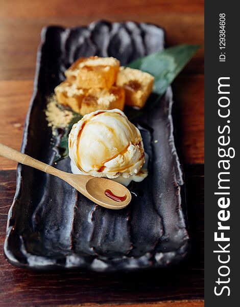 Warabi Mochi served with a scoop of vanilla ice cream that topping with caramel served in black plate