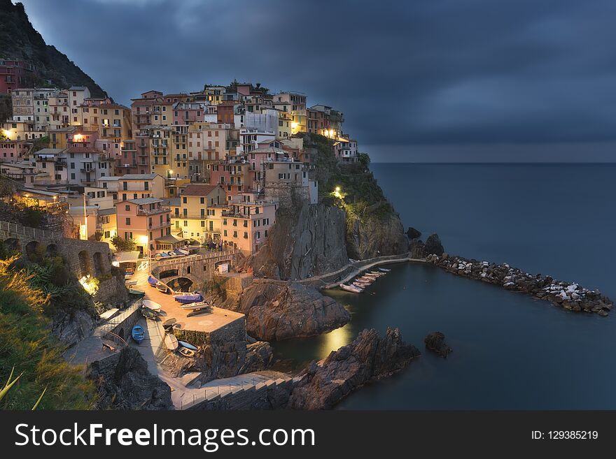 Amazing view of Manarola city at evening light with costal rocks on a foreground. Cinque Terre National Park, Liguria, Italy, Europe. Amazing view of Manarola city at evening light with costal rocks on a foreground. Cinque Terre National Park, Liguria, Italy, Europe.