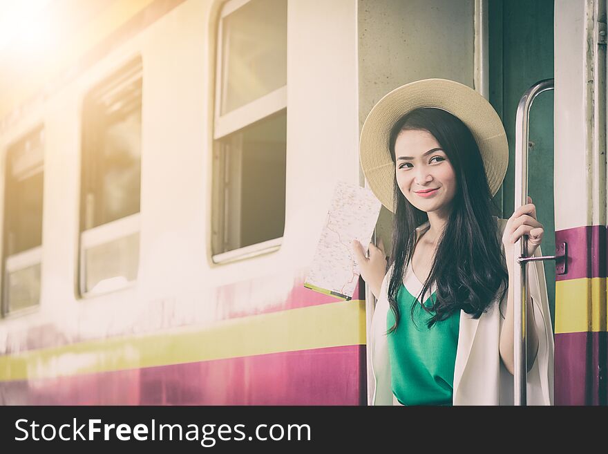 Asian woman traveler has get in the train with happiness at Hua Lamphong station at Bangkok, Thailand. beautiful brown cute door excited female girl green happy hat journey lifestyle looking map people purple railway smiling summer teen tourist transport transportation trip vacation white window yellow young