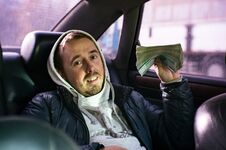 A Young Man Sitting In A Car With A Big Bundle Of Money. Stock Image