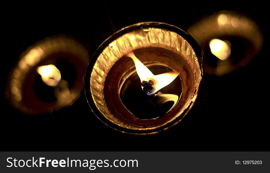 Closeup of three lit tea light candles burning with black background.