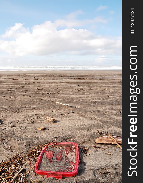 A colorful plastic container lid littering a sandy beach. A colorful plastic container lid littering a sandy beach.