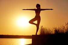 Silhouette Woman Practicing Yoga Or Stretching On The Beach Pier At Sunset Or Sunrise Stock Photo Silhouette Woman Practicing Yoga Or Stretching On The Beach Pier At Sunset Or Sunrise Stock Photo