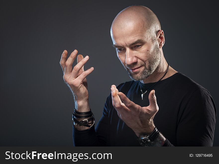 Brutal bald man, dark background, close-up
