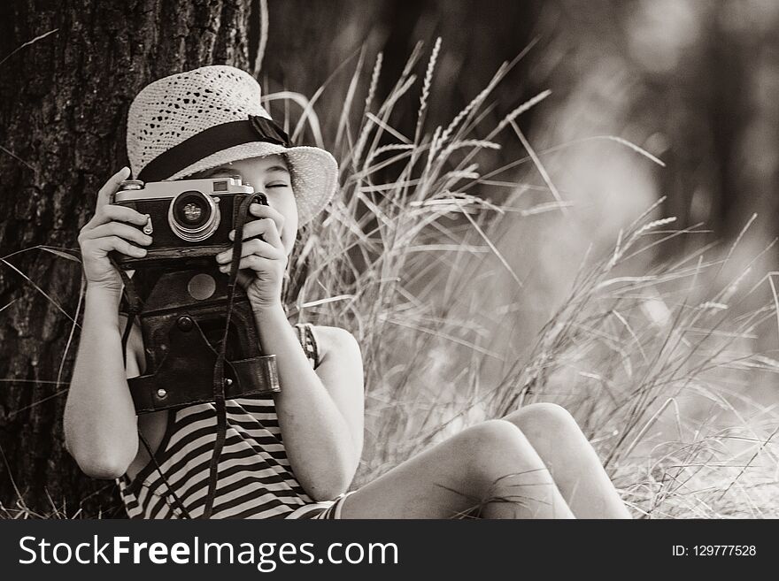 Photo of the beautiful girl taking photos with her camera near the tree . Image in black and white color style. Photo of the beautiful girl taking photos with her camera near the tree . Image in black and white color style