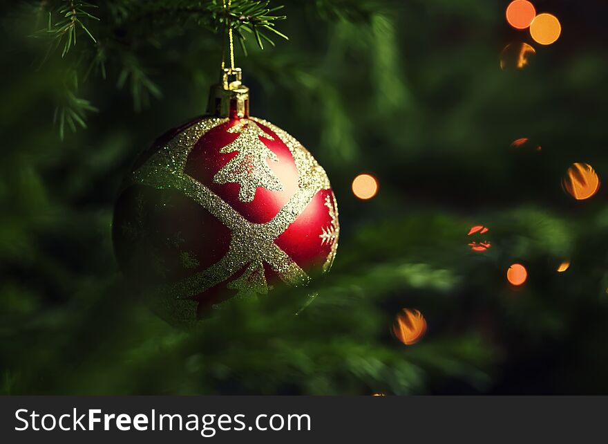 Red Christmas ball on the background of fir branches and lights