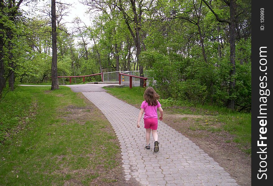 Young girl walking along a park pathway. Young girl walking along a park pathway.