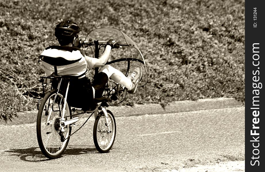 Man riding a unique bike with a windshield in sepia