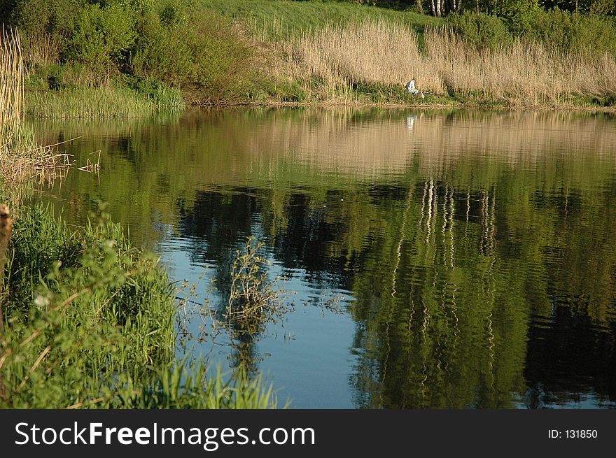 angler sitting opposite shore. angler sitting opposite shore