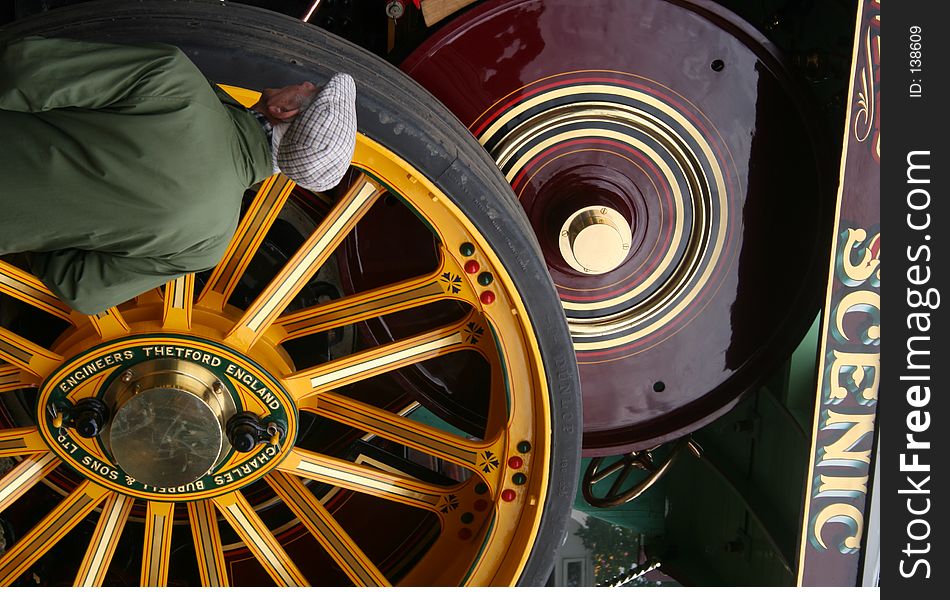 An old man takes a closer look at the workings of a traction engine. An old man takes a closer look at the workings of a traction engine