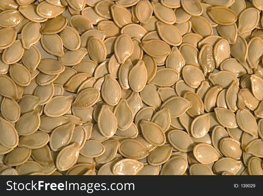 A closeup shot of pumpkin seeds crowded together on a tray. Abstract background. A closeup shot of pumpkin seeds crowded together on a tray. Abstract background.