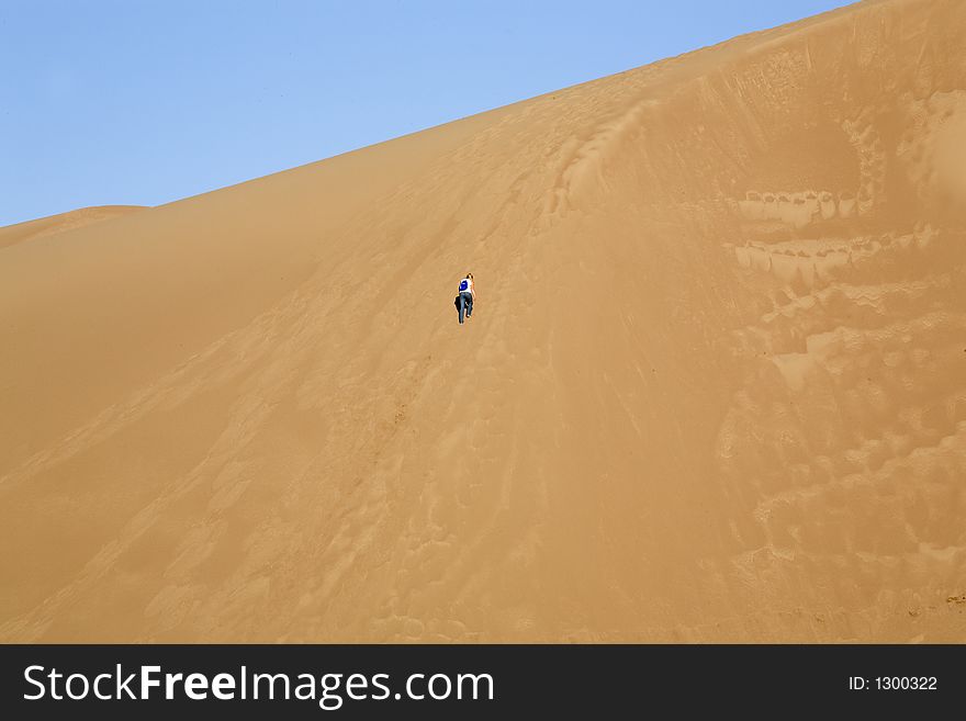 Girl climbing a very large sand dune. Girl climbing a very large sand dune