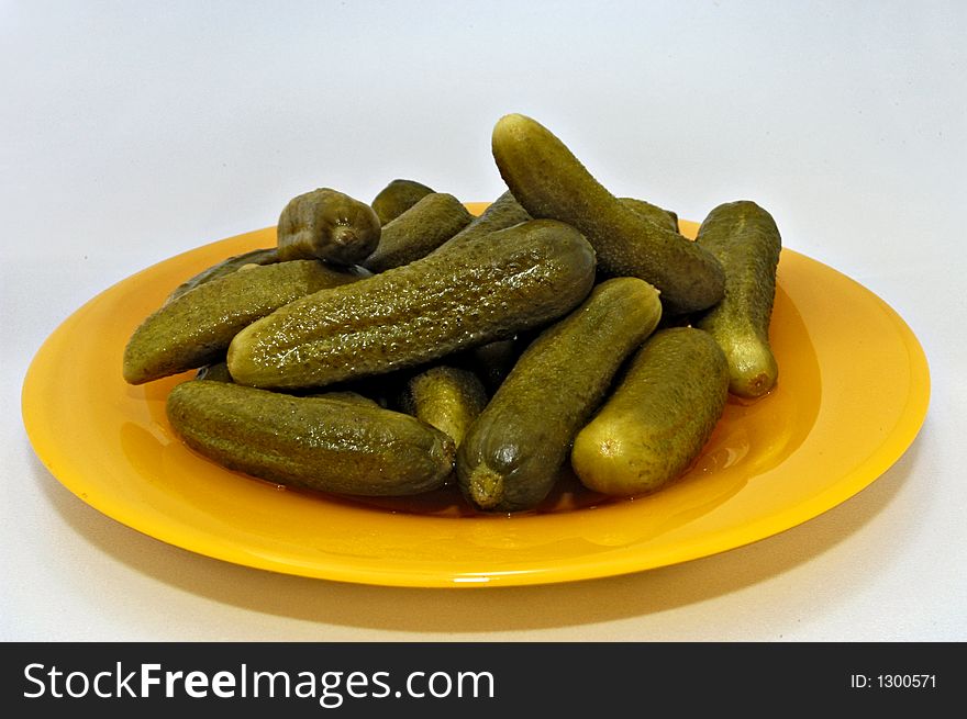 Pickled gherkins on yellow-orange plate on white endless backgroung. Pickled gherkins on yellow-orange plate on white endless backgroung.