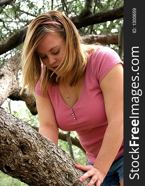 Teenage girl looking down while climbing a tree.
