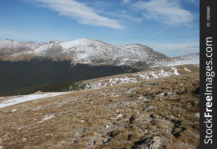 Barren terrain of alpine tundra in the foreground with mountian peaks in the distance. Barren terrain of alpine tundra in the foreground with mountian peaks in the distance.