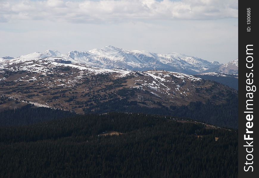 Barren terrain of alpine tundra in the foreground with mountian peaks in the distance. Barren terrain of alpine tundra in the foreground with mountian peaks in the distance.