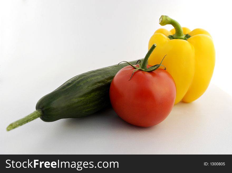 Vegetables - yellow bell pepper, cucumber and tomato on white endless background.