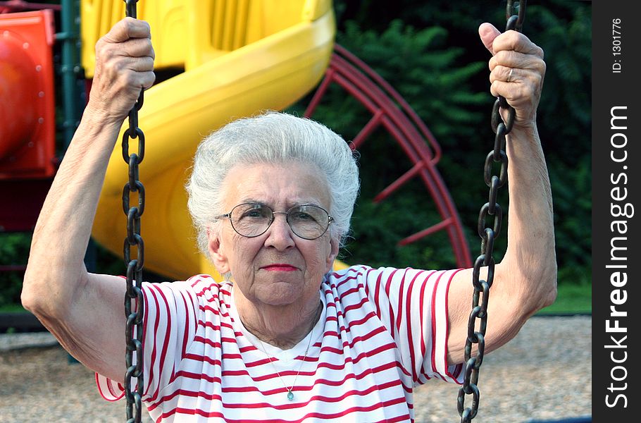 Senior citizen woman sitting on a playground swing. Senior citizen woman sitting on a playground swing.