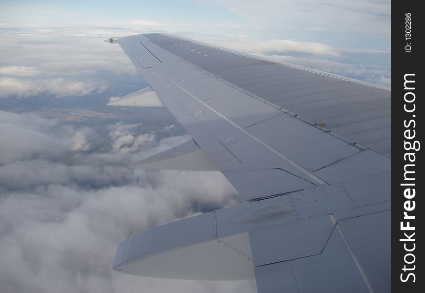 View from plane over the wing to clouds underneath. View from plane over the wing to clouds underneath.