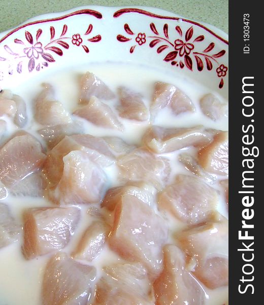 Chopped up chicken breast marinading in milk. Chopped up chicken breast marinading in milk