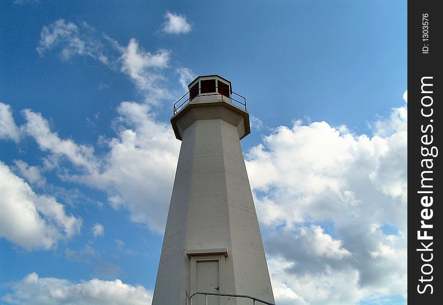 A lighthouse stands tall with clouds in the background. A lighthouse stands tall with clouds in the background