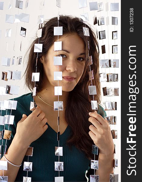 Beautiful young woman hiding behind mirrored hanging beads. Beautiful young woman hiding behind mirrored hanging beads