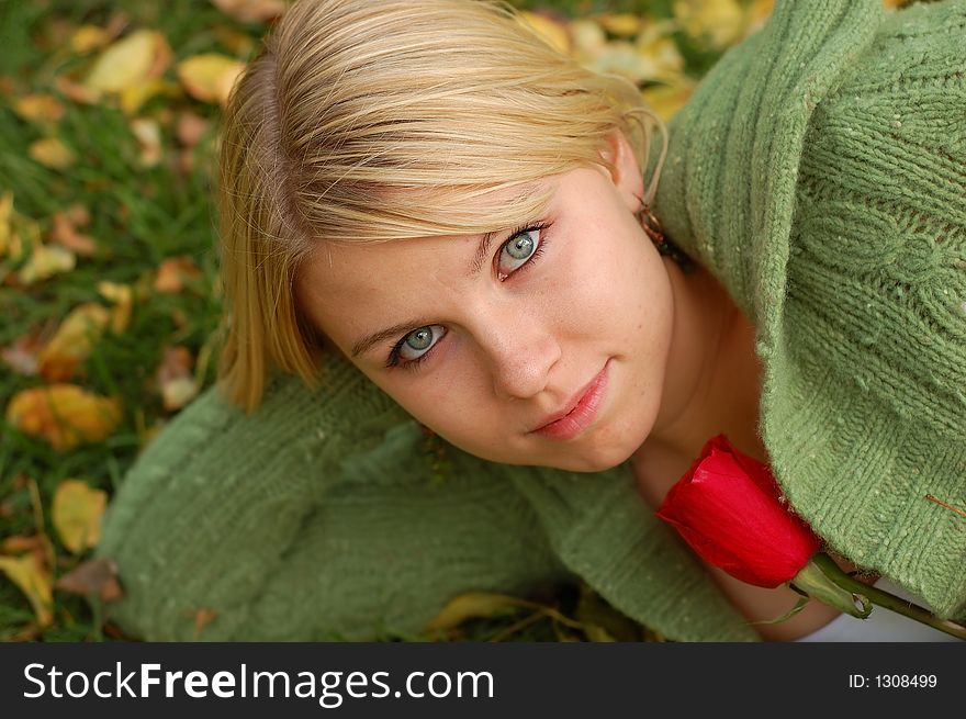 Beautiful girl holding red rose on bed of fall leaves. Beautiful girl holding red rose on bed of fall leaves.