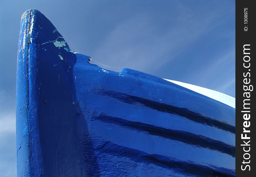 Blue wooden boat photographed on a dry dock from worm's eye view against the blue sky. Blue wooden boat photographed on a dry dock from worm's eye view against the blue sky