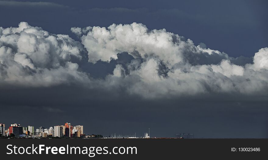 Long shot of skyscrappers near sea with stormy clouds over them