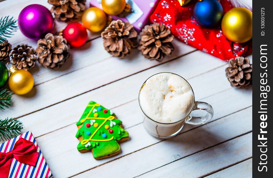 Photo of the beautiful Christmas decorations, gift, fir-tree shaped cookie and cup of coffee on the white wooden background. Photo of the beautiful Christmas decorations, gift, fir-tree shaped cookie and cup of coffee on the white wooden background