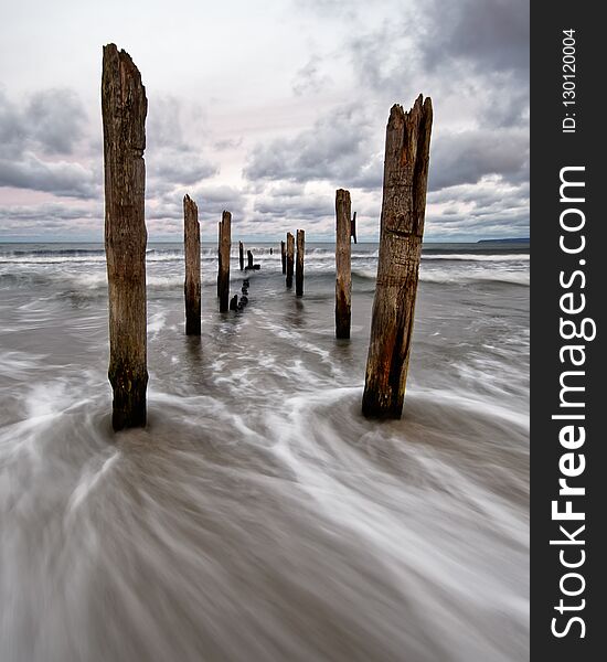 Wooden poles on the beach, water movement in long exposure