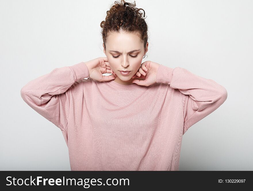 Beautiful young woman with curly hair , wearing pink long-sleeved sweater. Lifestyle concept. Close up.